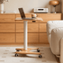 Cary solid oak movable small desk with laptop and mug in a bright living room setting