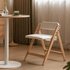 Corese Natural Solid Oak Folding Chair with light oak frame and ivory cushion, styled next to a round dining table.