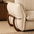 Detailed view of the cream striped sofa arm with soft upholstery, curved wooden frame and polished metal rail.