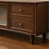 Close-up of the storage drawer on a dark wood TV unit with a brass knob and natural wood grain.