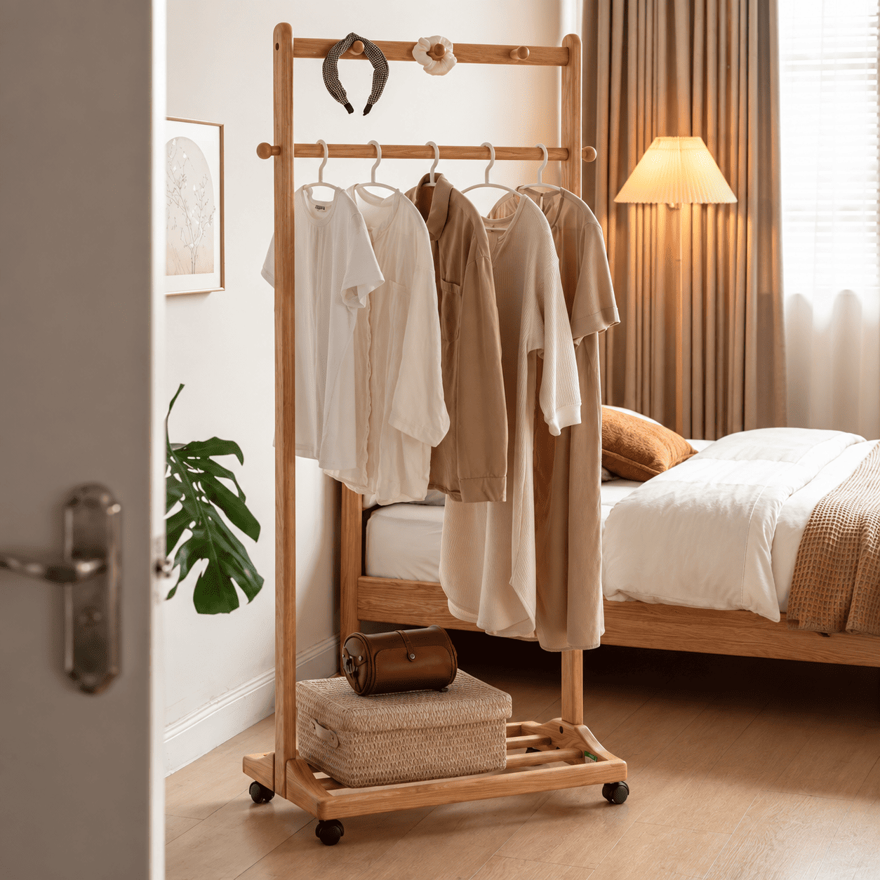Fukuoka natural solid oak movable coat rack with neutral clothing and storage basket beside bed