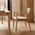 Graz Natural Solid Ash Dining Chair in natural wood finish with tapered legs, rounded armrests and cushioned grey seat beside a dining table