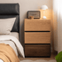 Herman Mix Timber Modular Chest of Drawers beside a bed, featuring stacked drawers in light and dark timber tones.