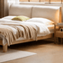 Modern oak bed featuring a padded fabric headboard, solid wood frame, and clean-lined silhouette