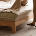 Scandinavian-style wooden bed frame with a cream upholstered headboard and natural oak finish