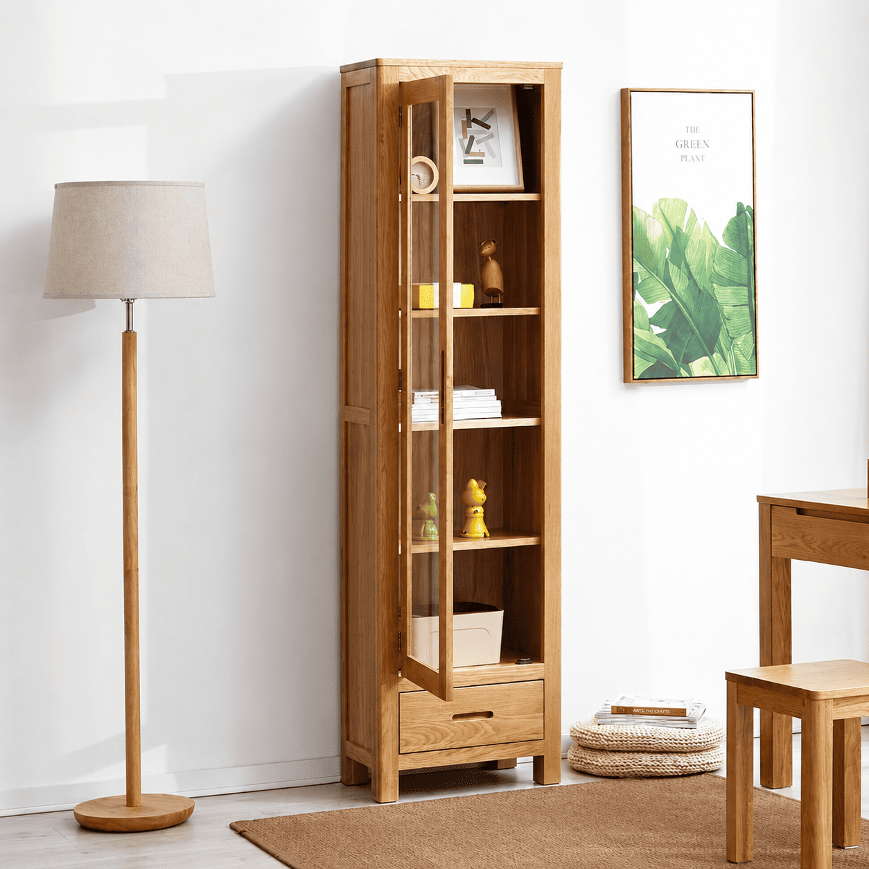 Humbie Solid Oak Slim Display Cabinet with glass door, lower drawer and natural oak finish in a bright living room.