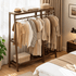 Lahti natural solid walnut double coat rack with hanging clothes and top storage shelf beside bedroom window