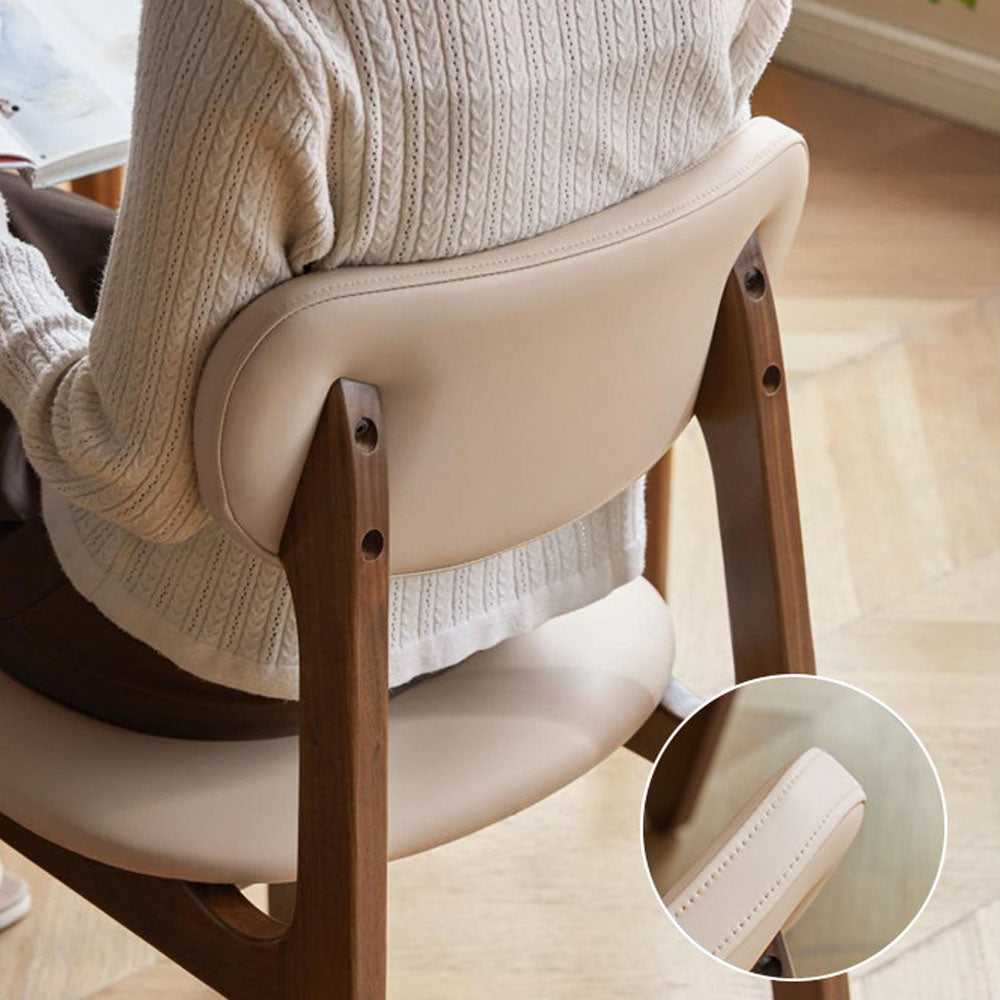 Marche solid walnut dining chair with warm white vegan leather cushion, shown beside a dining table in a bright modern dining space.