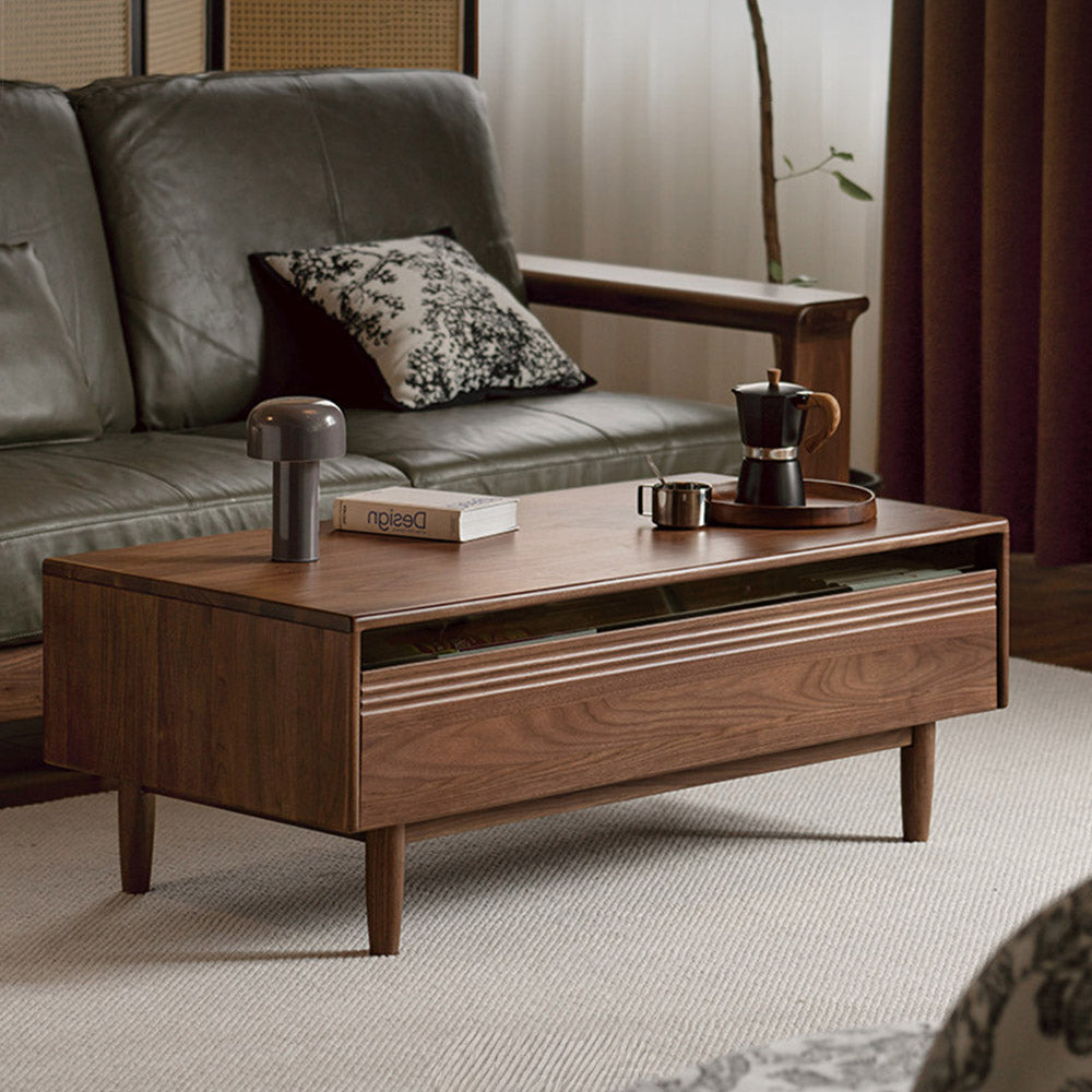 Modena natural solid walnut coffee table with glass-accented drawers and elevated legs in a modern living room setting