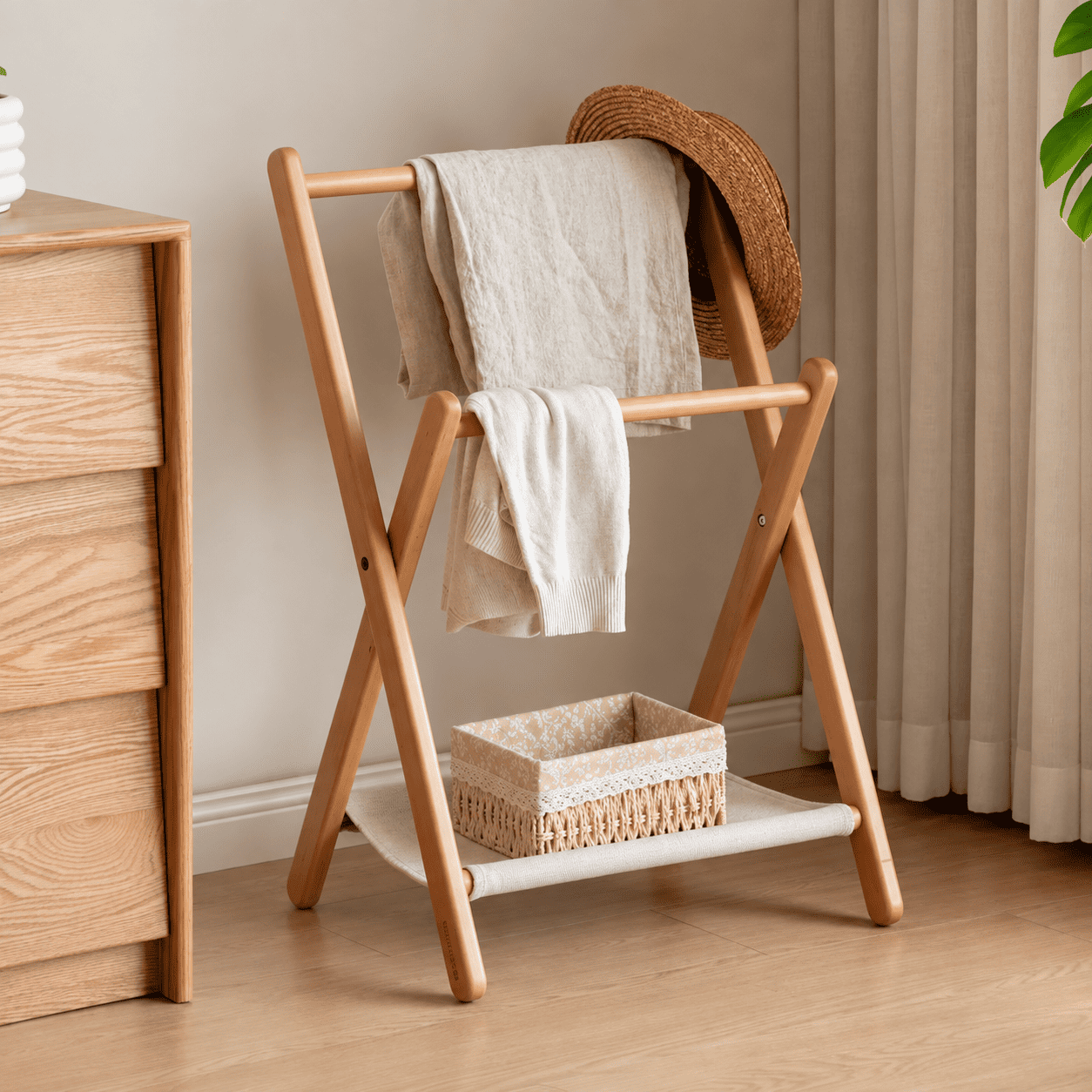 Naila natural solid beech coat rack styled with folded towels and storage basket