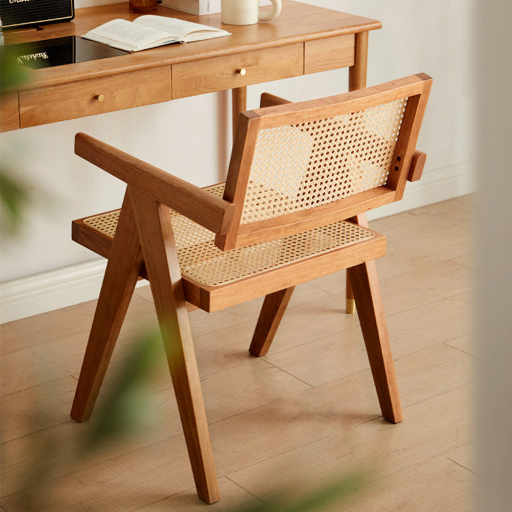 Nordic solid cherry designer chair with woven Indonesian rattan seat and backrest, featuring timber armrests and an angled frame in a sunlit room.