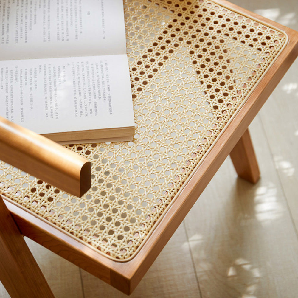 Nordic solid cherry designer chair with woven Indonesian rattan seat and backrest, featuring timber armrests and an angled frame in a sunlit room.