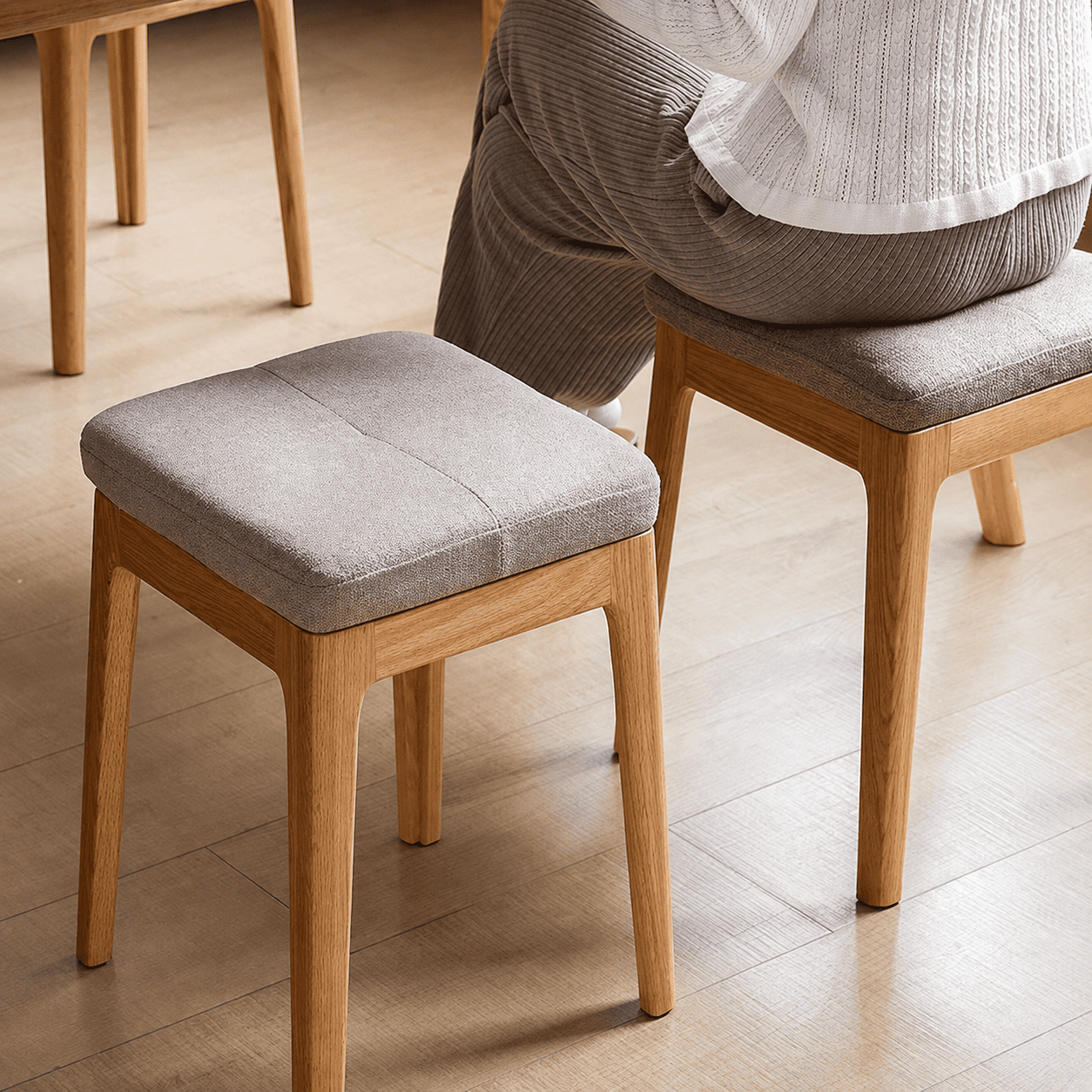 Modern wooden nesting stool set featuring upholstered seats and a natural oak finish