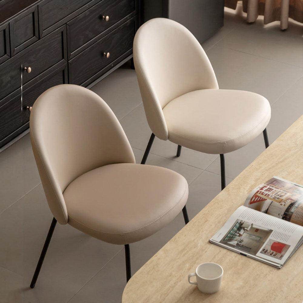 Loreto faux leather dining chair with curved backrest and matte black metal legs, shown in warm white/light brown upholstery.