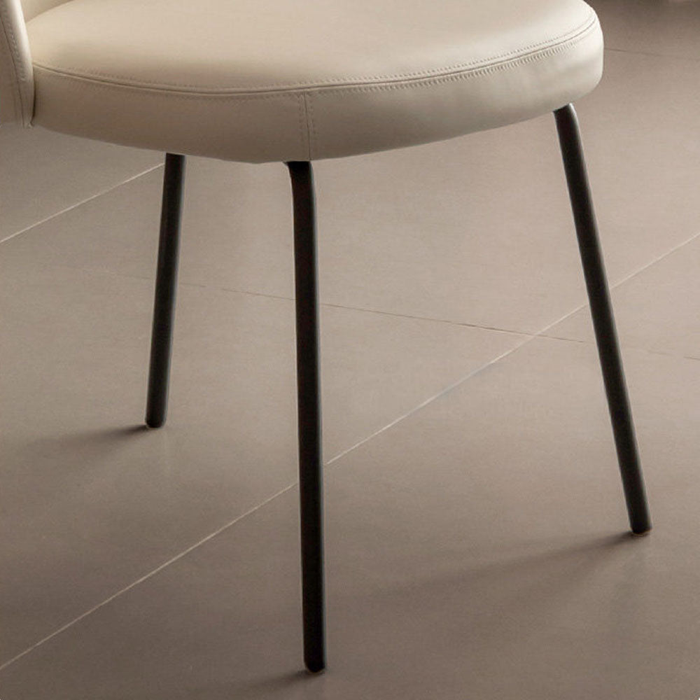 Loreto faux leather dining chair with curved backrest and matte black metal legs, shown in warm white/light brown upholstery.