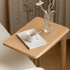 Compact wooden side table with wheels, open storage shelf, and minimalist design