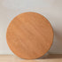 Natural solid cherry small round dining table in a warm timber finish, shown in a compact dining space with dining chairs and kitchen backdrop