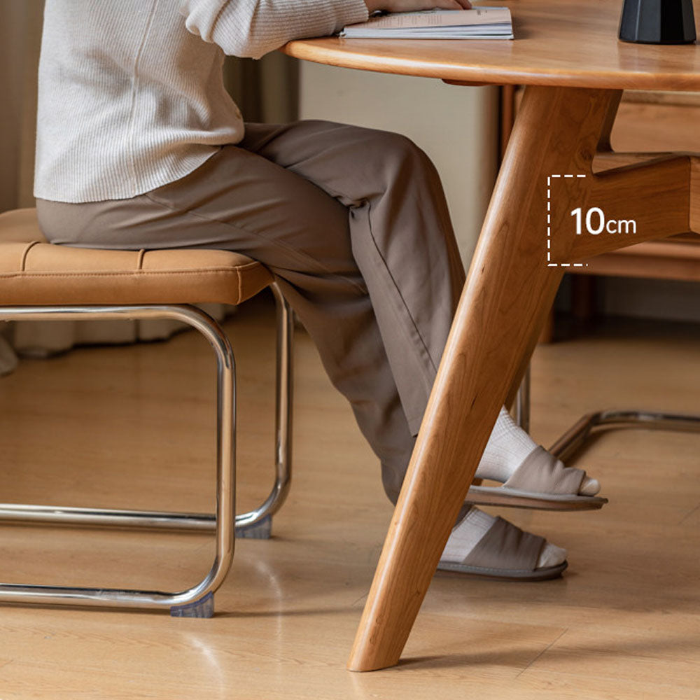 Natural solid cherry small round dining table in a warm timber finish, shown in a compact dining space with dining chairs and kitchen backdrop