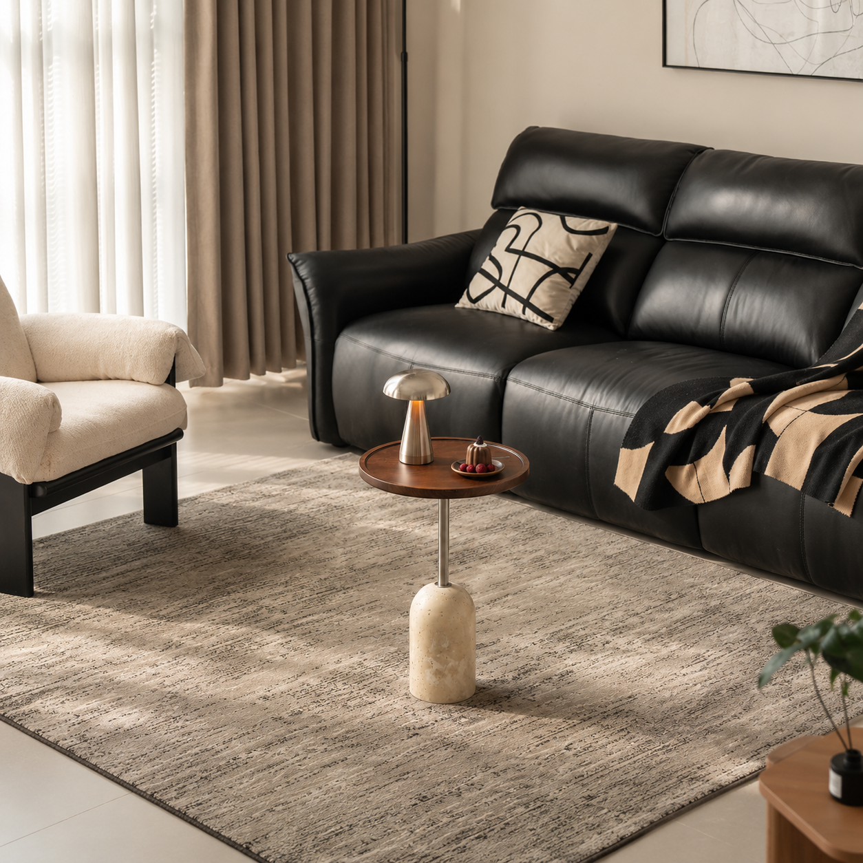 Round walnut side table with travertine base styled in a modern living room with a black leather sofa.