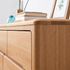 Close-up of a light oak wood dresser with drawers, showing the wood grain texture and a clean interior drawer pull.