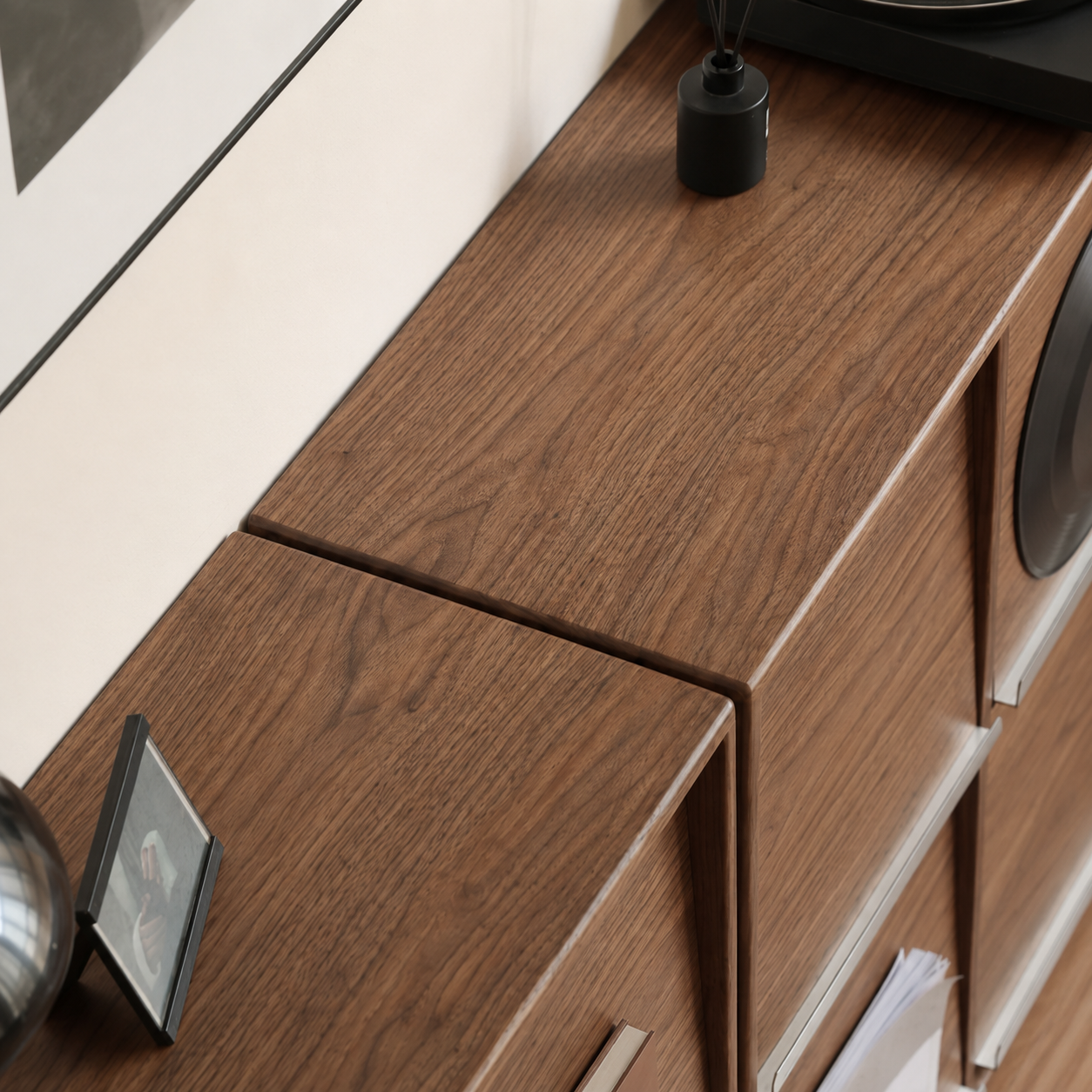 Close-up of walnut storage cabinet showing open bottle storage and brushed metal rail details.